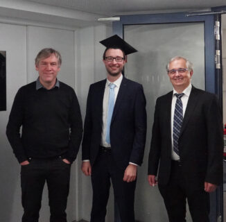 The photo shows Prof. Lenz, Andreas Maximilian Wahl and Prof. Kapitza after the doctoral examination. All three men stand next to each other. Andreas Maximilian Wahl is in the middle and wears an academic hat. All three smile at the camera.